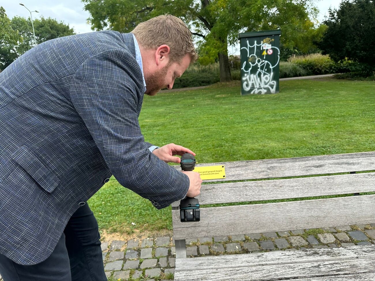 wethouder schroeft plaquette op bankje